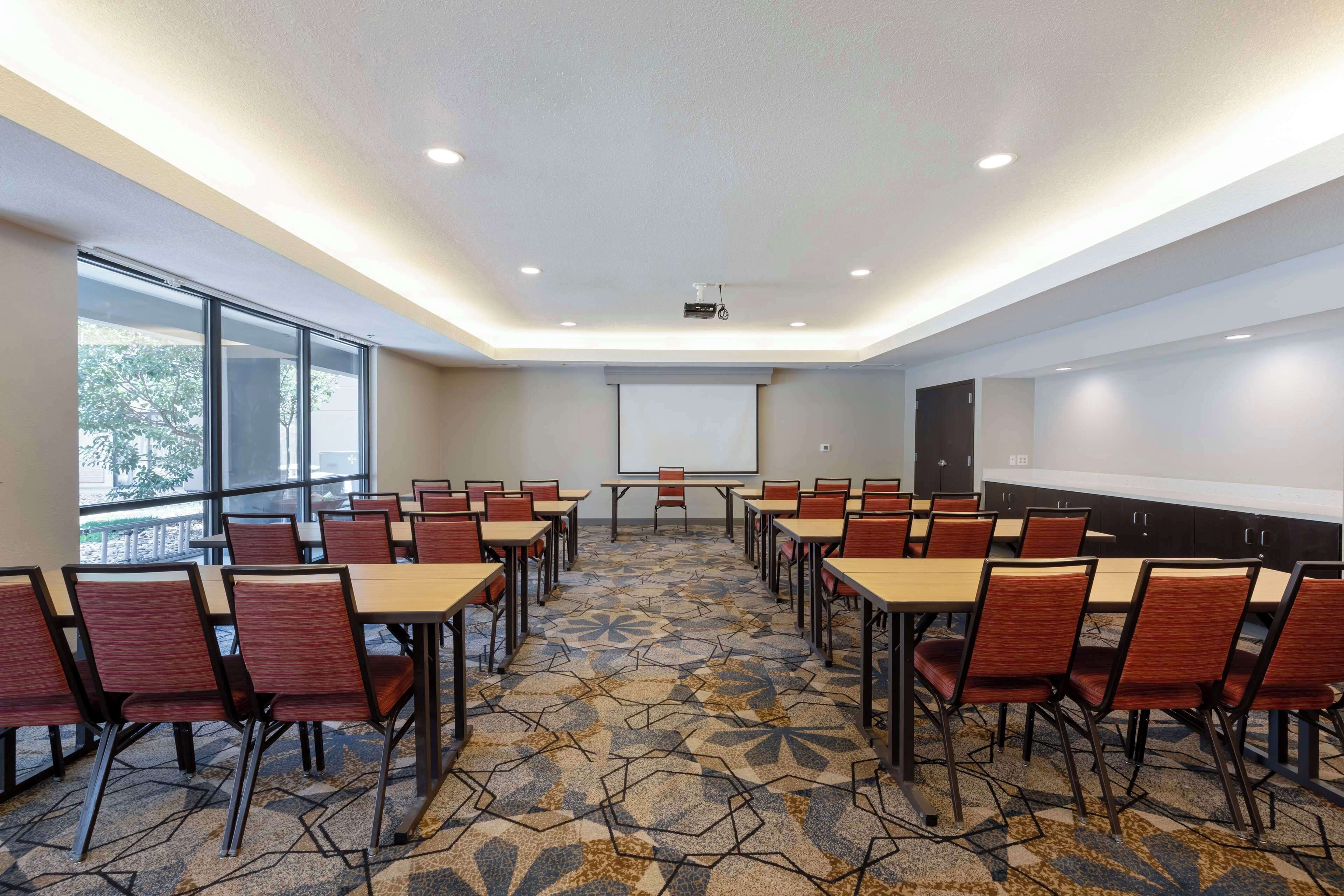 A conference room with tables and chairs, a projector, and a whiteboard.