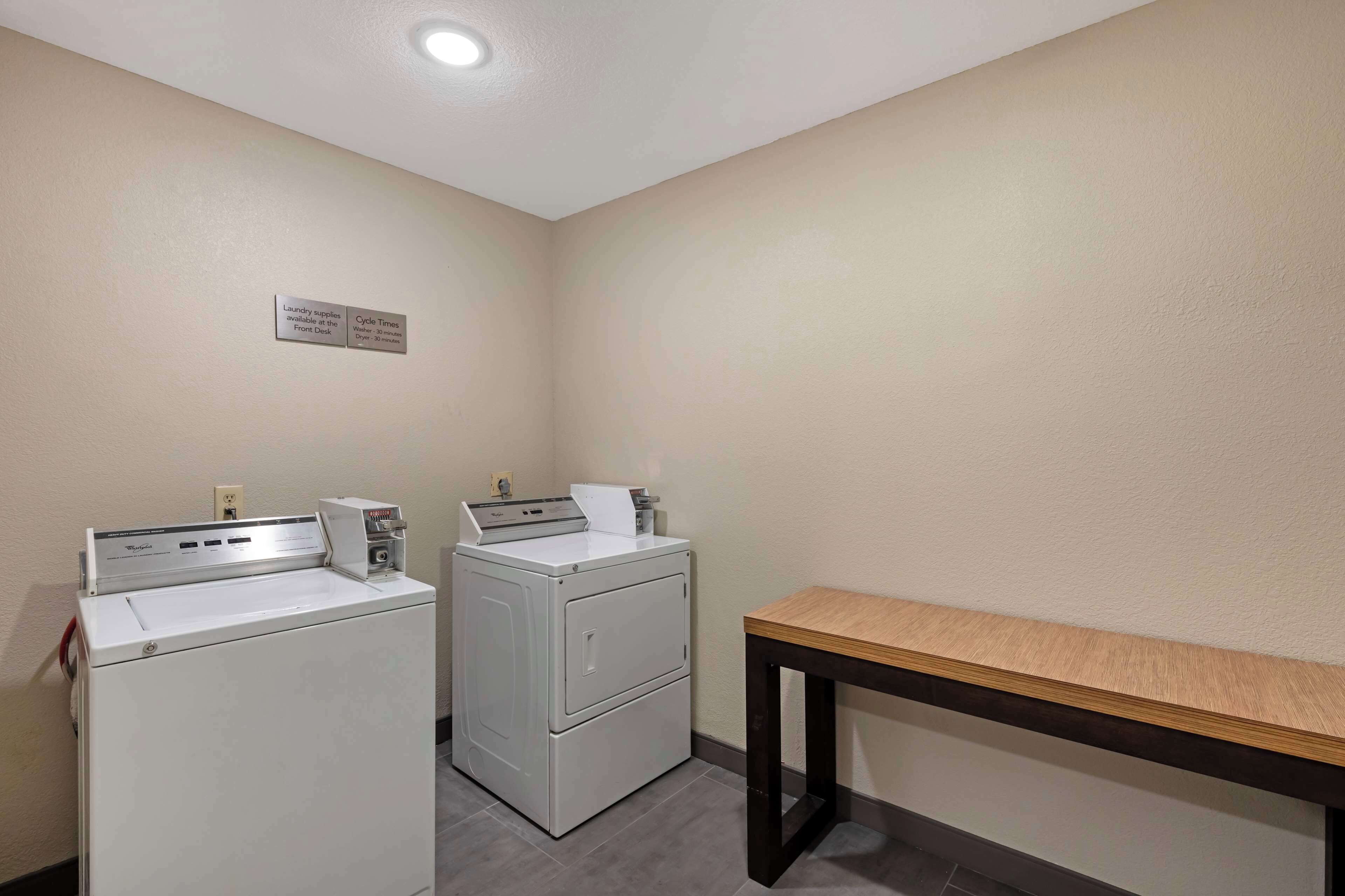 A laundry area with two front-loading washing machines and a table.