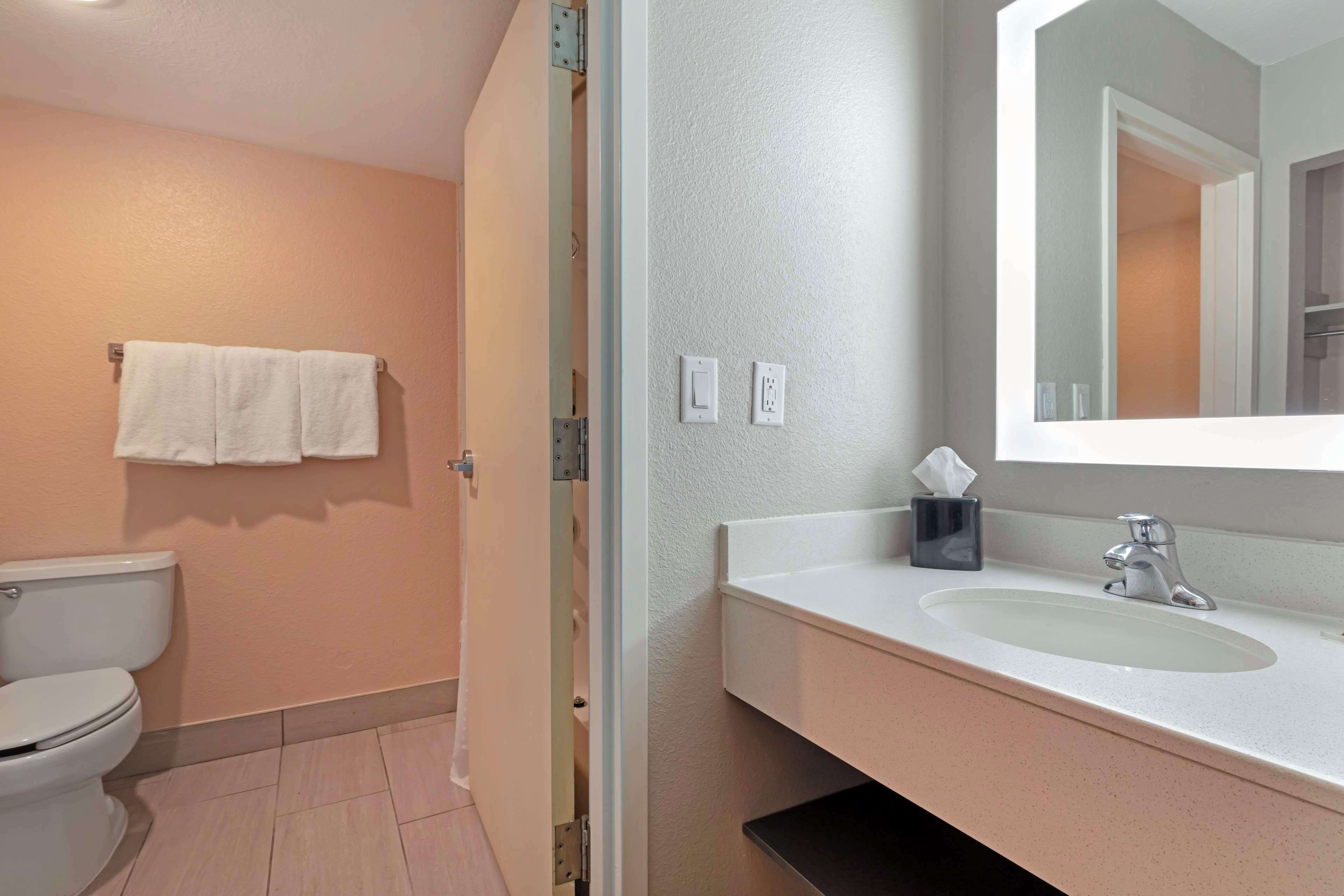 A bathroom with a toilet, sink, mirror, and towel rack.