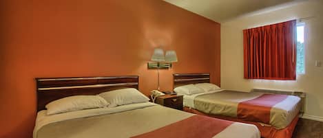 Una habitación de hotel con dos camas, una mesita de noche con lámpara y una ventana con cortinas rojas.