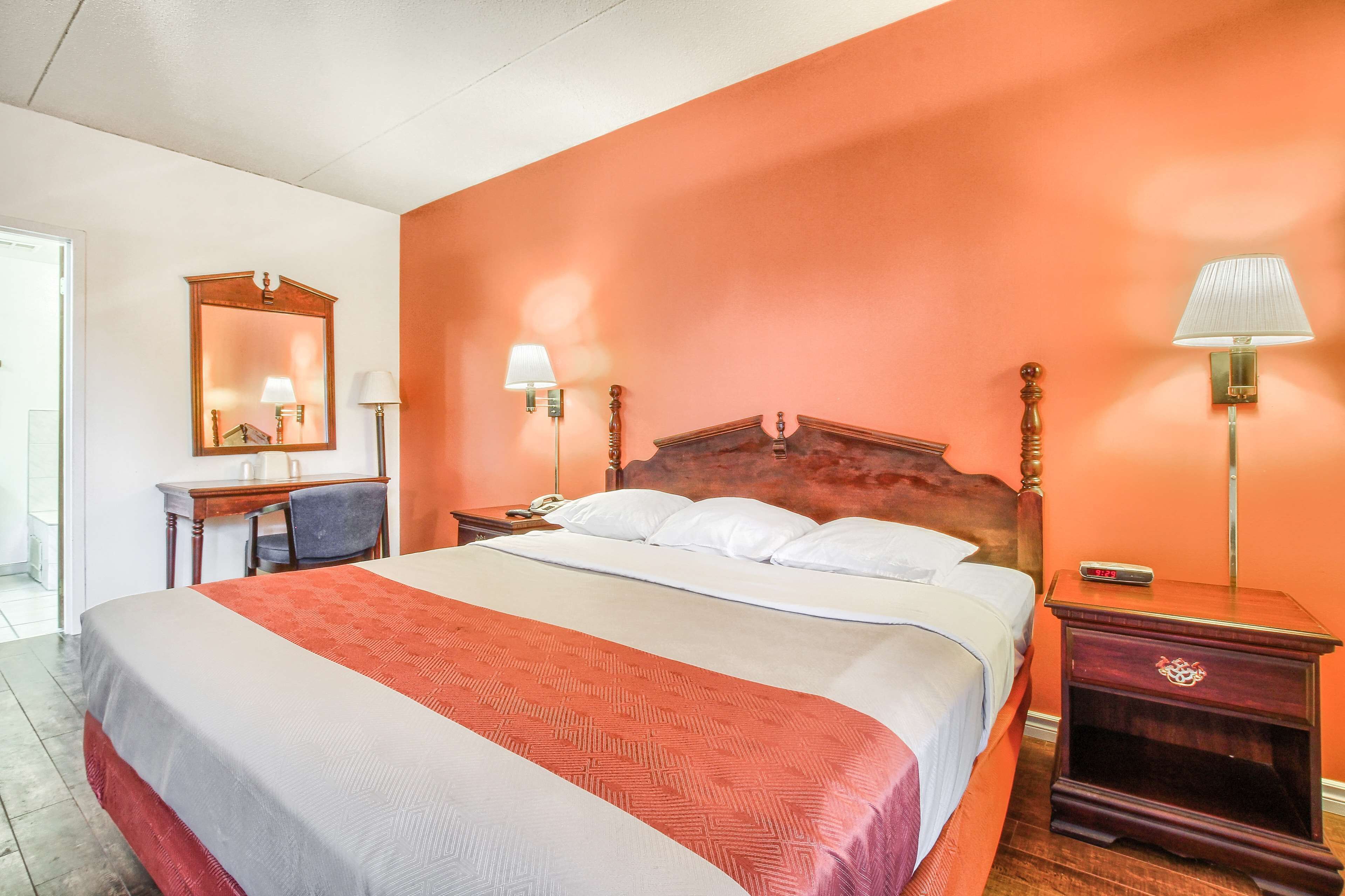 A hotel room with a large bed, two bedside tables, a desk, and a chair.