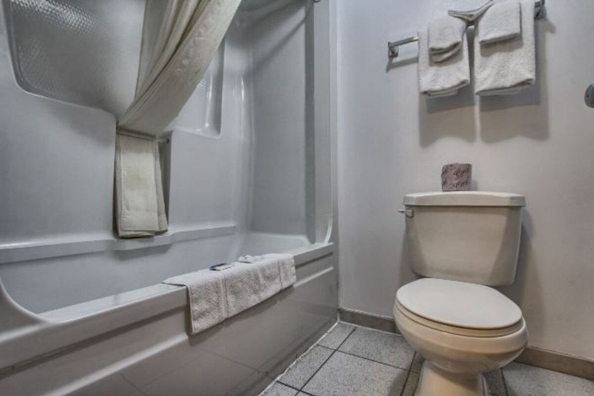 A bathroom with a bathtub, toilet, and a towel rack.
