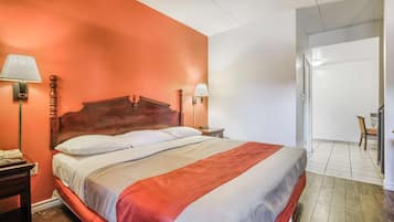 Habitación de hotel con una cama grande, dos lámparas de noche, una mesita de noche y una silla en la esquina.