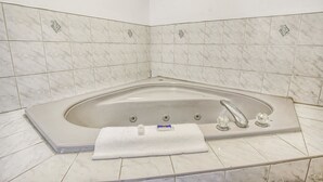 A bathroom with a freestanding bathtub, a towel, and a marble-tiled wall. - Motel 6 Windsor, ON (Windsor)