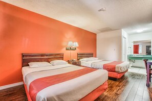 Quarto de hotel com duas camas, banheiro com pia verde e um espelho.