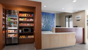 A hotel reception area with a self-service beverage station, a microwave, and a counter with a sign for the Marriott Bonvoy hotel. - Fairfield Inn & Suites Fort Worth/Fossil Creek (Fort Worth)