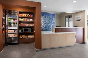 A hotel reception area with a self-service beverage station, a microwave, and a counter with a sign for the Marriott Bonvoy hotel.