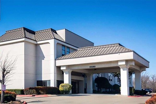 A modern building with a covered entrance and a parking lot.