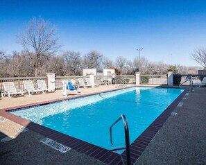 A rectangular swimming pool with a no diving sign, surrounded by lounge chairs and a fence.
