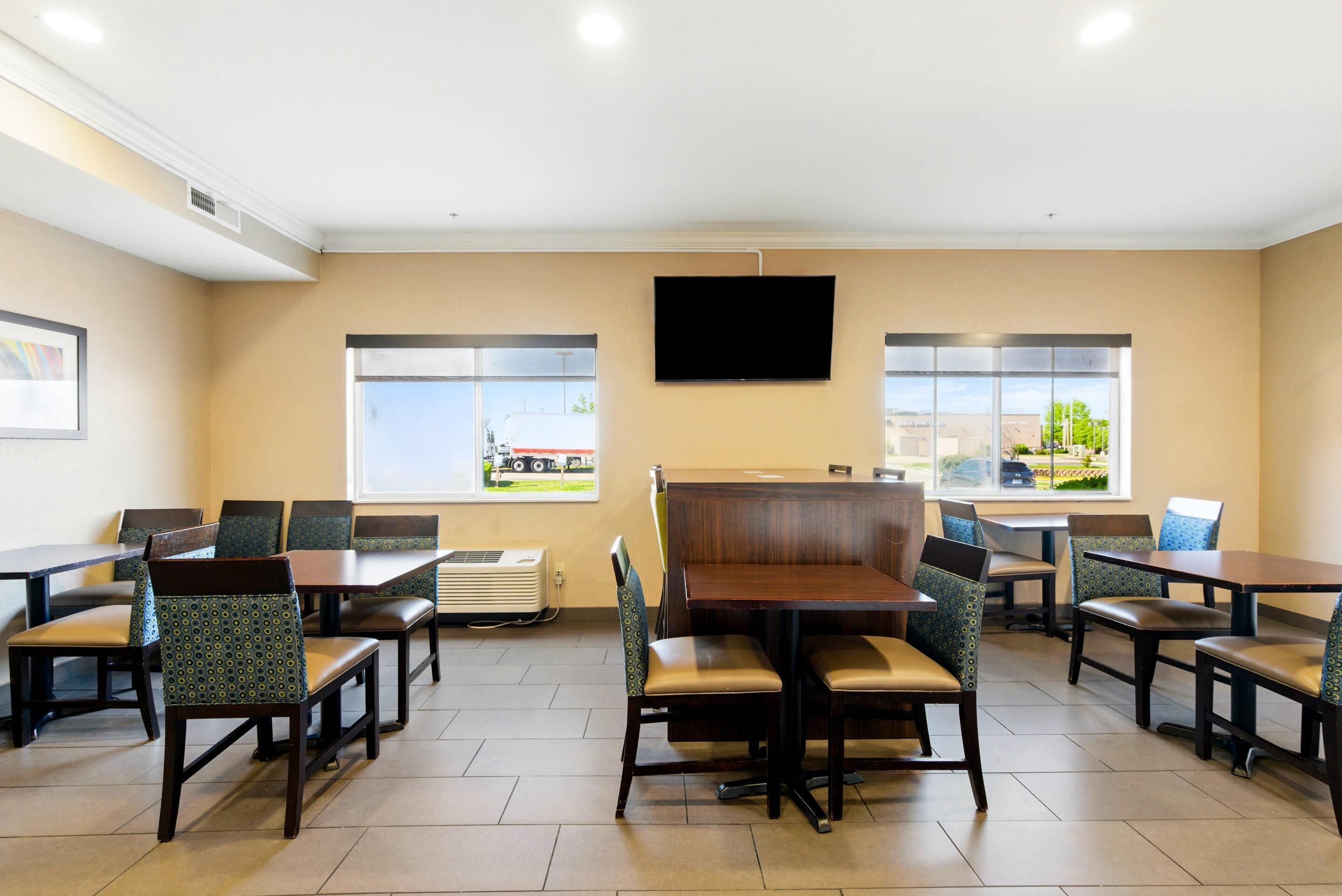 A restaurant with booths and tables, large windows, and a flat-screen TV on the wall.