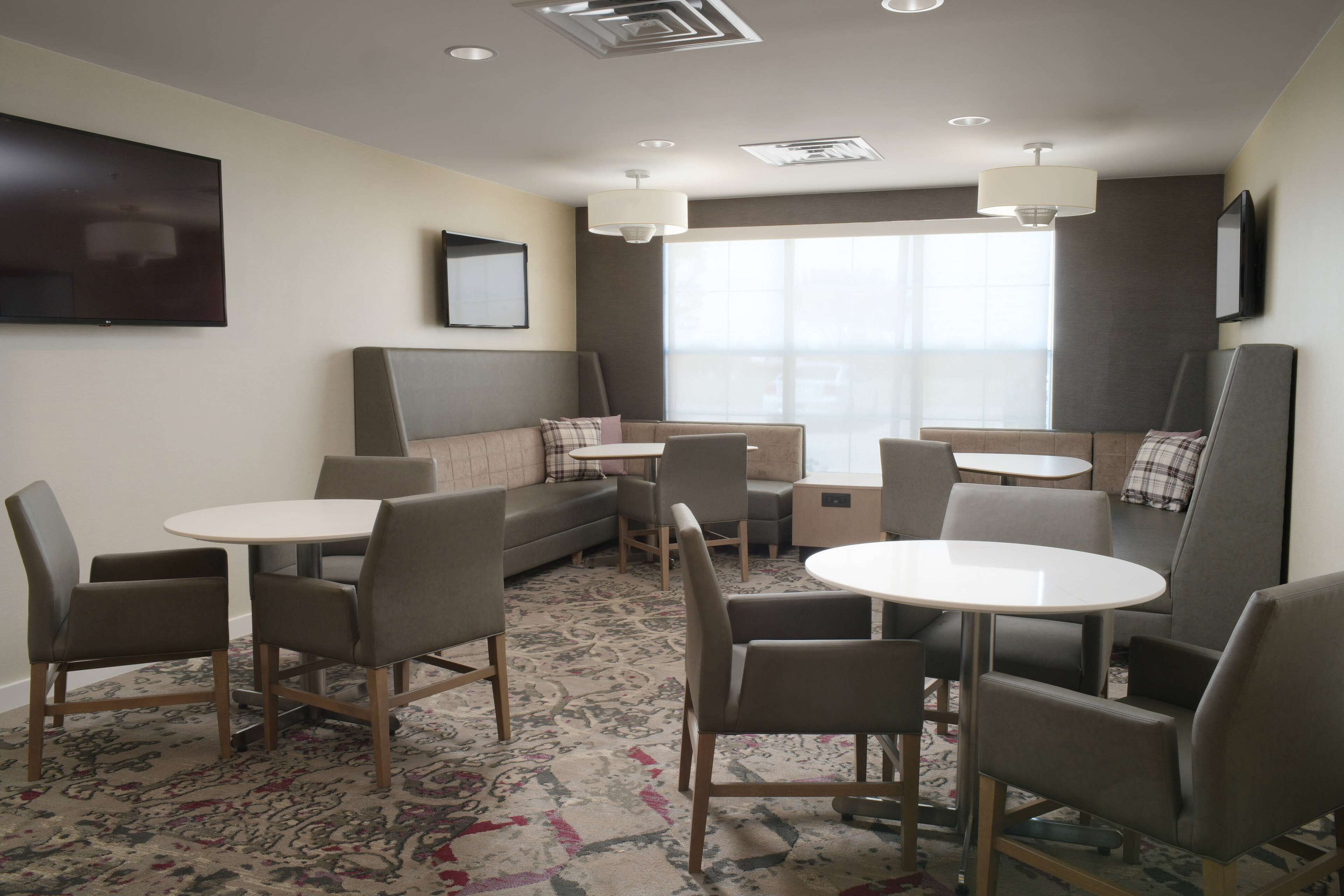 Une chambre d’hôtel avec un canapé, deux tables rondes et quatre chaises.