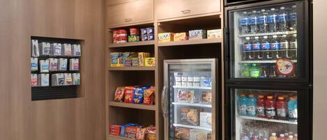 A vending machine with various snacks and drinks, a refrigerator with beverages, and a shelf with packaged goods.