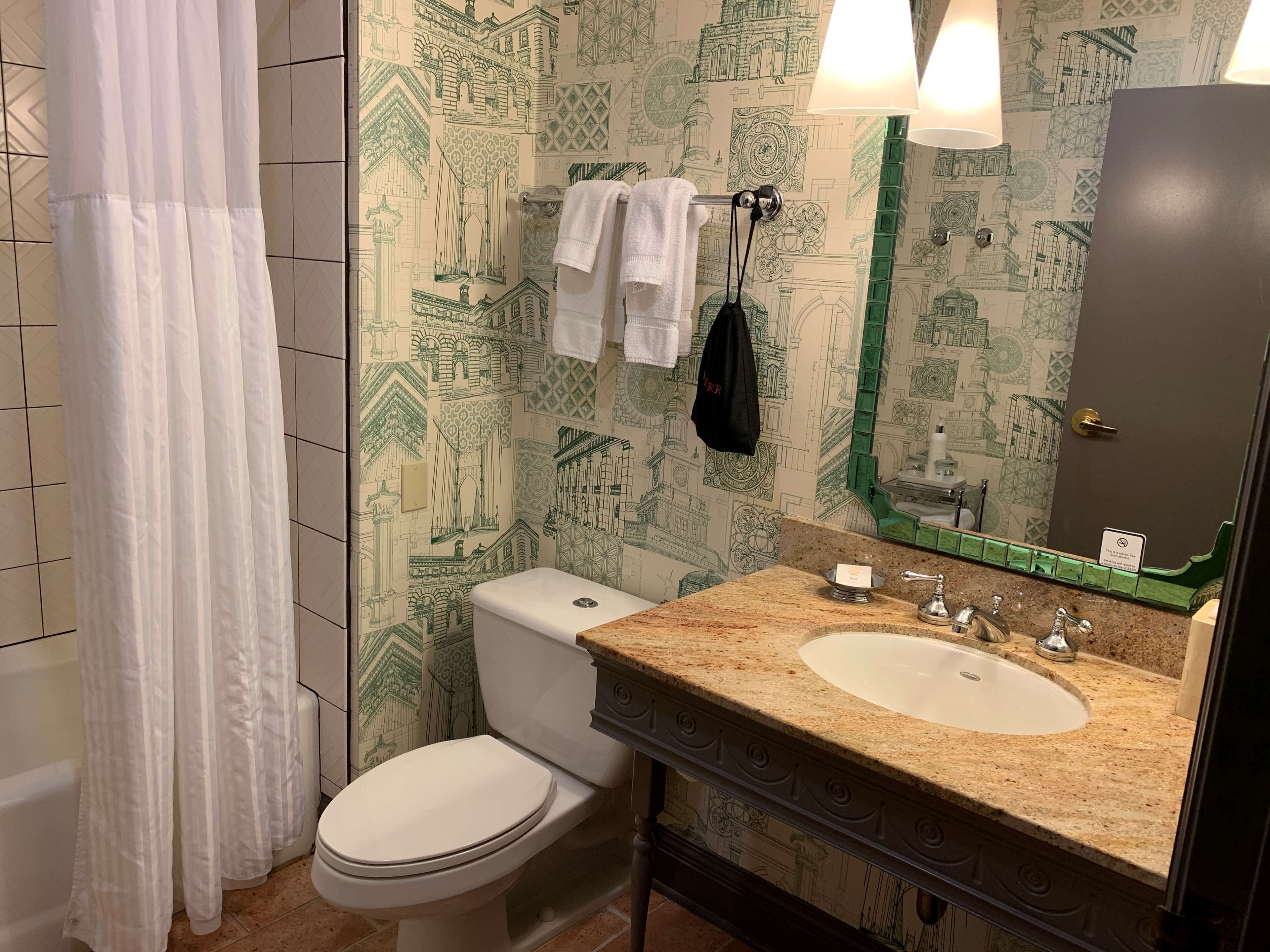 A bathroom with a toilet, sink, and mirror.
