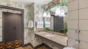 A bathroom with patterned wallpaper, a sink with a mirror, and two towel racks.