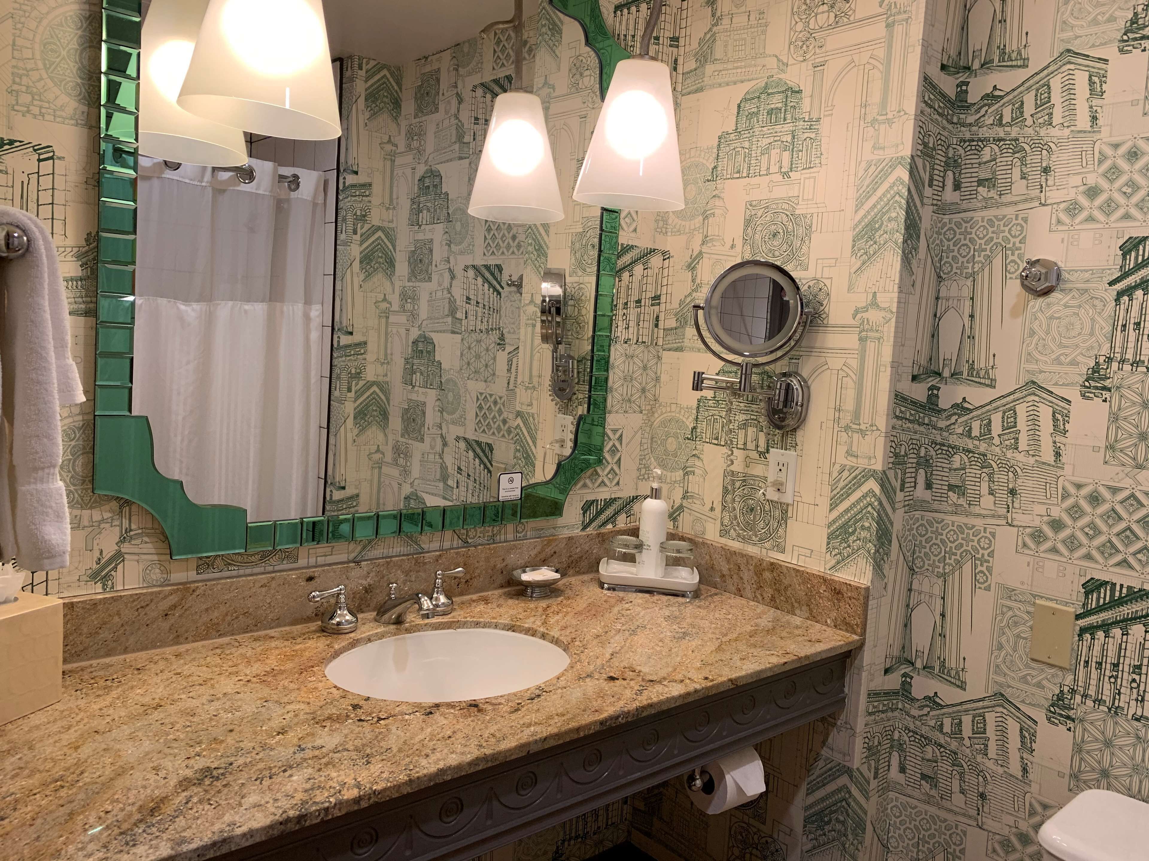 A bathroom with a sink, mirror, and green towel rack.