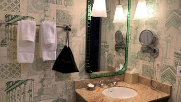 Ein Badezimmer mit Waschbecken, Spiegel, Handtuchhalter und ornamentalem Wandpapier.