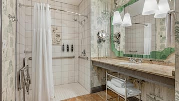 A bathroom with a shower, a vanity with a mirror and lights, and a towel rack.
