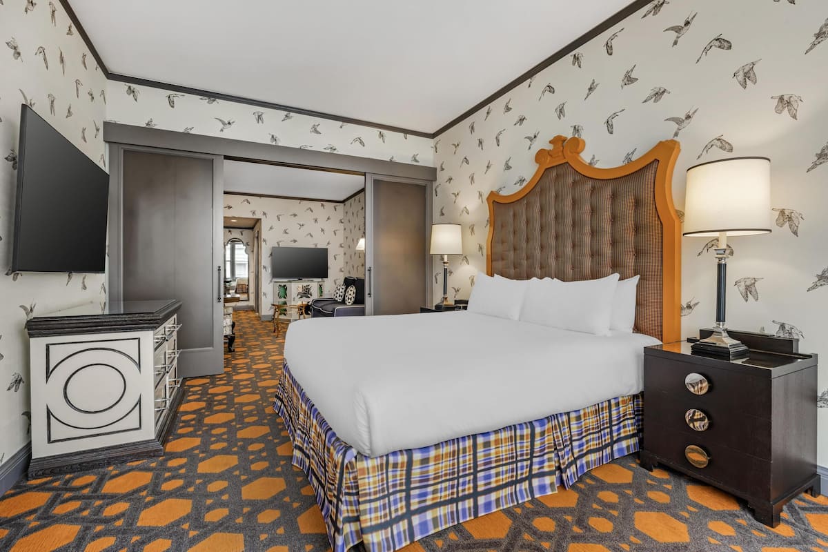A hotel room with a large bed, a TV, a desk, and a nightstand.