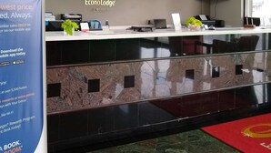 En hotelfri reception med et skilt for EconoLodge, en reklame for en mobilapp og et fjernsyn monteret på væggen.