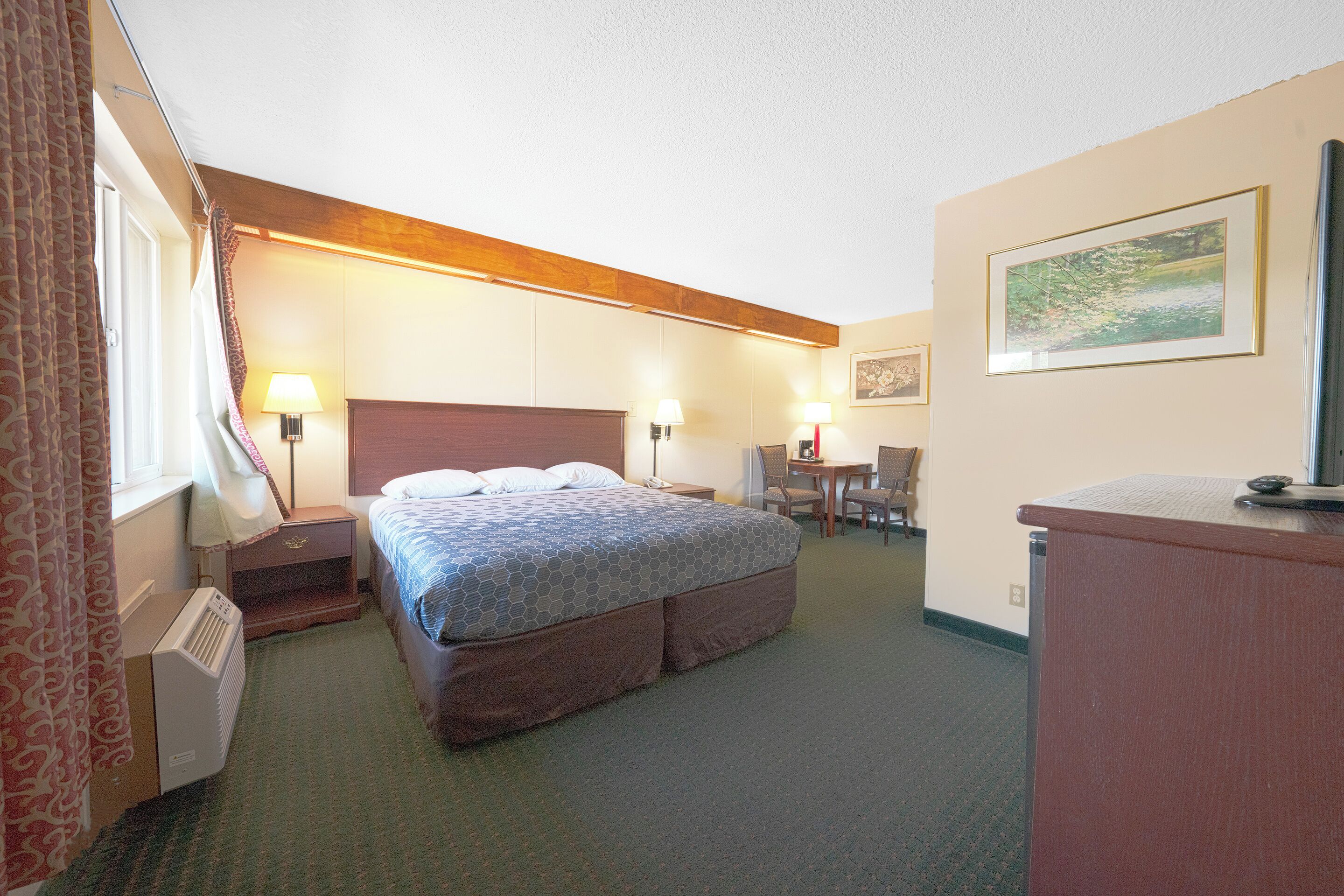A hotel room with a large bed, bedside lamps, a desk, and a chair.