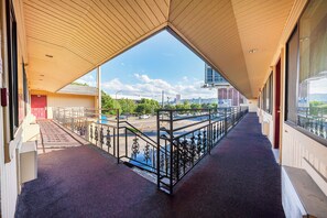 A covered outdoor corridor with a view of a parking lot and cityscape.