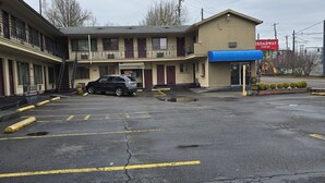 A motel with a parking lot, a staircase leading to the entrance, and a sign for Broadway Inn. - Broadway Inn (Portland)