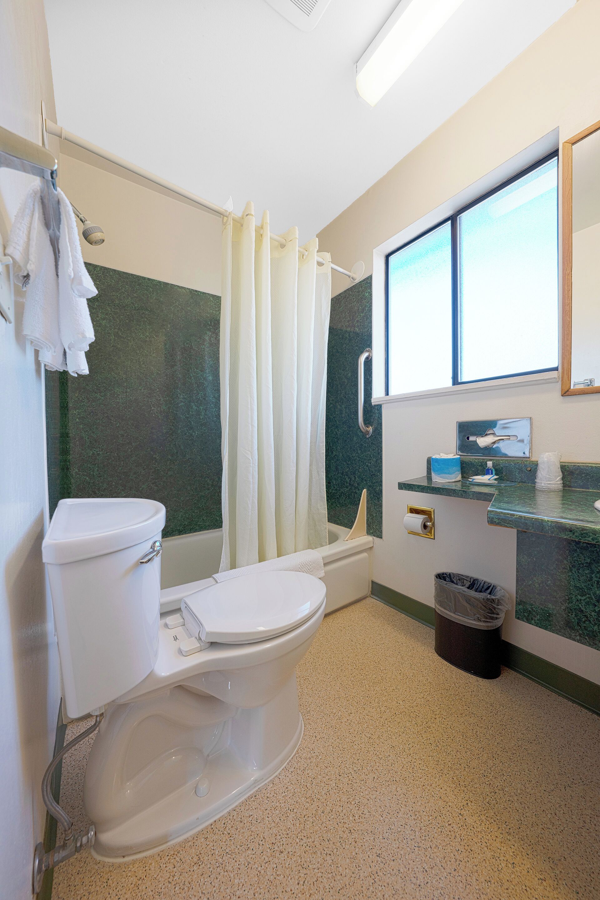 A bathroom with a toilet, shower, and sink.