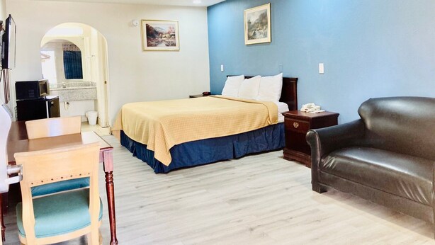 A hotel room with a bed, a desk, a chair, a sofa, and a small kitchenette. - Americas Best Value Inn & Suites Houston Brookhollow NW (Houston)