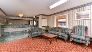 A lobby with striped wallpaper, a reception desk, two patterned sofas, a wooden coffee table, and a red patterned carpet. - Americas Best Value Inn & Suites Houston Brookhollow NW (Houston)