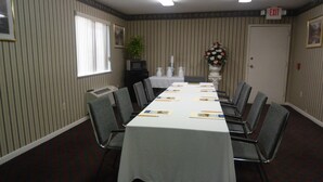 A conference room with a long table, chairs, a potted plant, and an exit sign. - Americas Best Value Inn & Suites Houston Brookhollow NW (Houston)