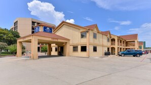A hotel with a beige facade, multiple entry points, and a parking lot. - Americas Best Value Inn & Suites Houston Brookhollow NW (Houston)