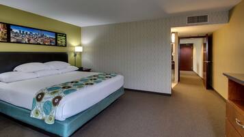 A hotel room with a large bed, a nightstand, a lamp, and a painting on the wall.