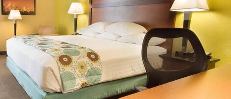 A hotel room with a bed, two bedside lamps, a chair, and a table.