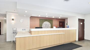 A hotel reception desk with a wooden counter, a clock, and a water dispenser.