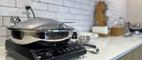A kitchen with a induction cooktop and a stainless steel pot on it.