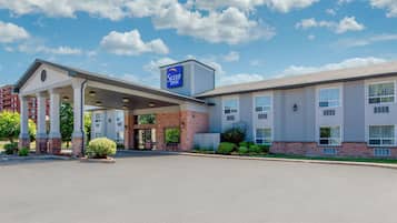 Welcome to Sleep Inn, where guests can enjoy a peaceful stay amidst beautifully maintained gardens and a covered entrance.