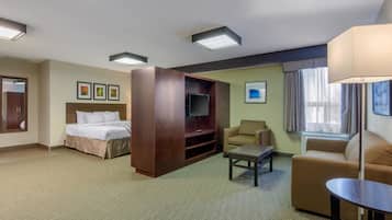 A hotel room with a bed, a TV, a sofa, a coffee table, and a desk.
