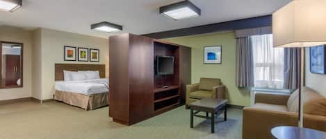 A hotel room with a bed, a TV, a sofa, a coffee table, and a desk.
