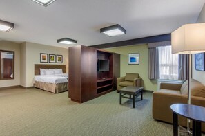 Una habitación de hotel con cama, televisor, sofá, mesa de centro y escritorio.