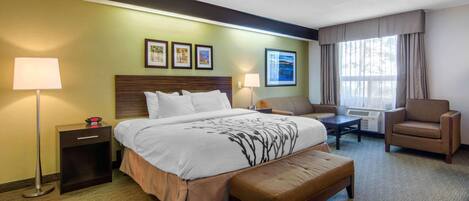 A hotel room with a large bed, bedside tables, a chair, a desk, and a window with curtains.