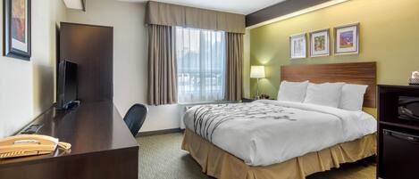 A hotel room with a bed, desk, chair, and a television.