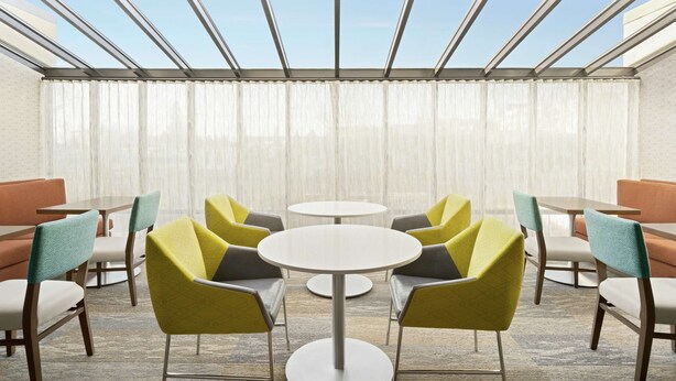 A hotel room with a skylight, a round table, and chairs with yellow and teal upholstery. - Hampton Inn Portland-Airport (Portland)