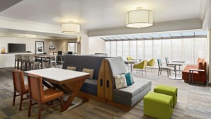 A modern hotel lobby with a dining area, seating arrangements, and a large window providing natural light. - Hampton Inn Portland-Airport (Portland)