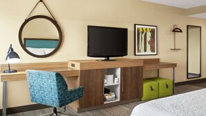 A hotel room with a bed, a desk with a computer, a television, a mirror, and a painting on the wall. - Hampton Inn Portland-Airport (Portland)