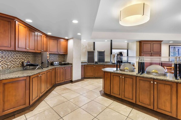 A modern kitchen with wooden cabinets, granite countertops, and a large island with a built-in oven.