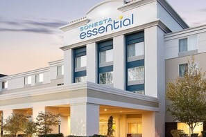 Un edificio moderno de hotel con un letrero que dice 'SONESTA essential'.