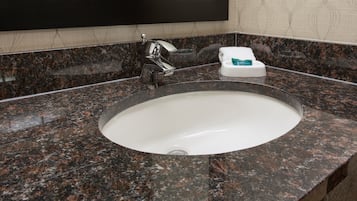 A bathroom sink with a granite countertop, a mirror, and a soap dispenser.
