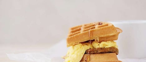 A stack of waffles with syrup and a pat of butter.