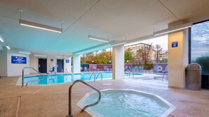 An indoor swimming pool area with clear signage, a hot tub, and a view of the outside. - Heritage Inn & Suites The Woodlands, Trademark by Wyndham (The Woodlands)