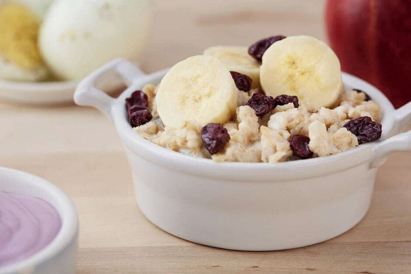 Un tazón de avena con plátanos y pasas.